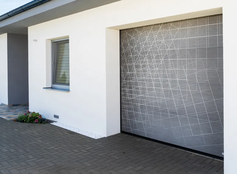 Moderní garážová brána s geometrickým vzorem na bílém domě.