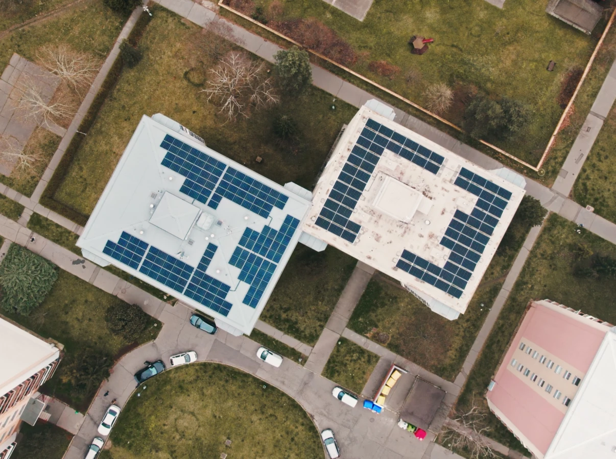Dvě domy s fotovoltaickými panely na střechách z výšky.