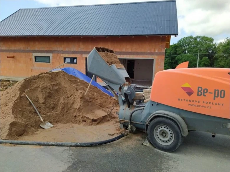 Stroj na betonování u hromady písku před stavbou.