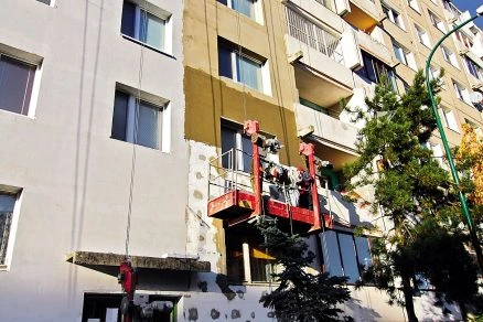 Práce na fasádě s použitím styropanu při rekonstrukci bytového domu.