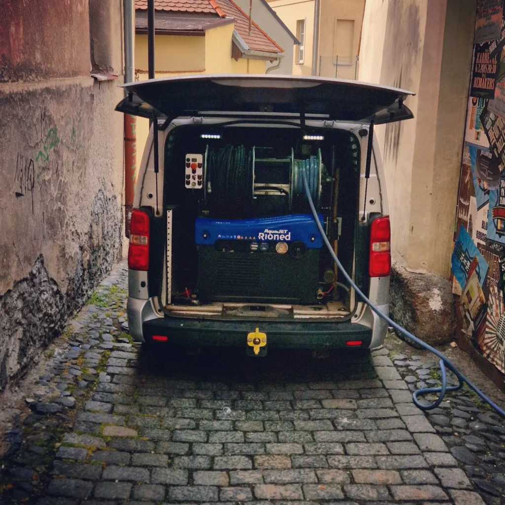 Stoupačka s čističkami vody zaparkovaná v úzké uličce.