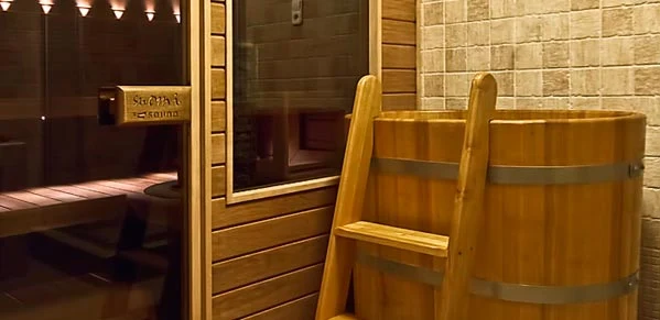 Dřevěný ochlazovací bazének s žebříčkem u vchodu do sauny.