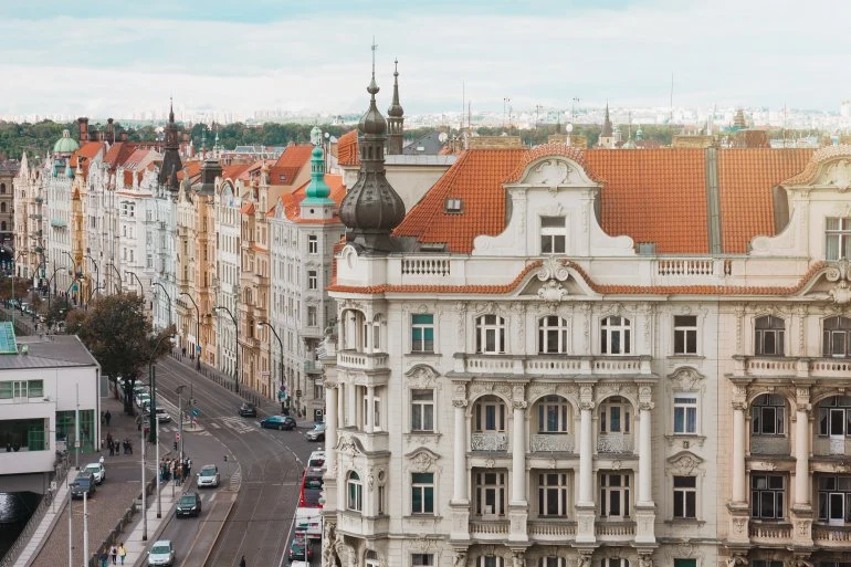 Historické budovy s bílými fasádami a červenými střechami na ulici.
