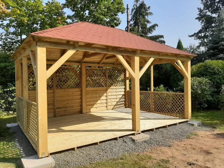 Nová dřevěná zahradní pergola s červenou střechou a mřížovými panely.