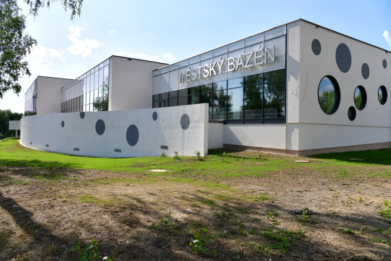 Fotografie krytého městského bazénu v Karviné s okrouhlými výřezy ve fasádě.