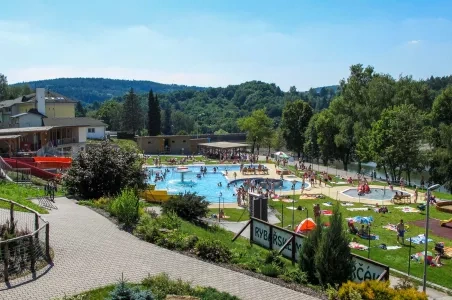 Venkovní bazén s vodními skluzavkami a soláři v lázeňském městě.