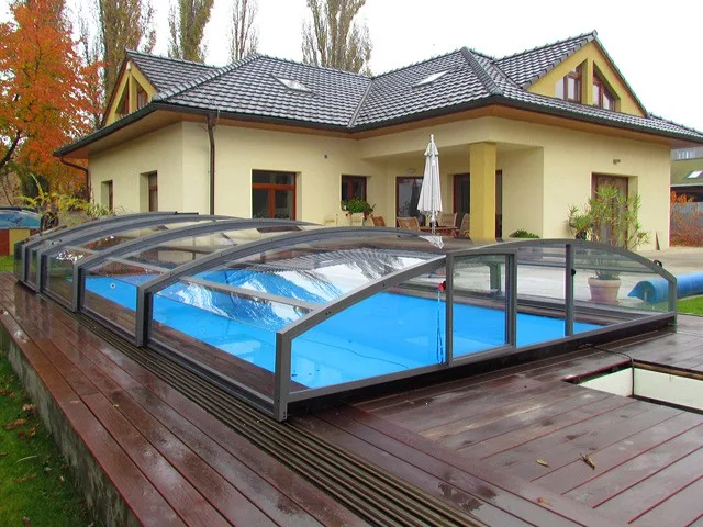 Moderní kryt bazénu s průhlednou střešní ochranou na dřevěné terase.