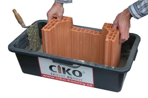 Ruční montáž cihlového komína v paletě s maltou