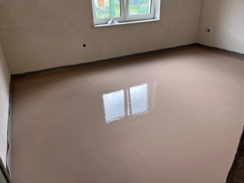 Hotový povrch podlahy z anhydritu v místnosti s oknem.