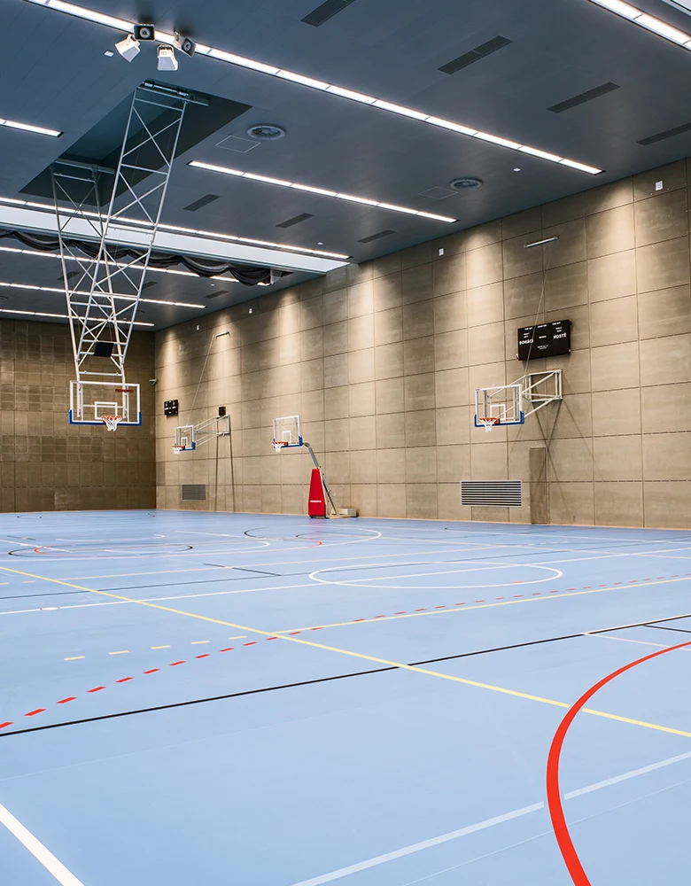 Vnitřní sportovní hala s modrou podlahou pro basketbal.