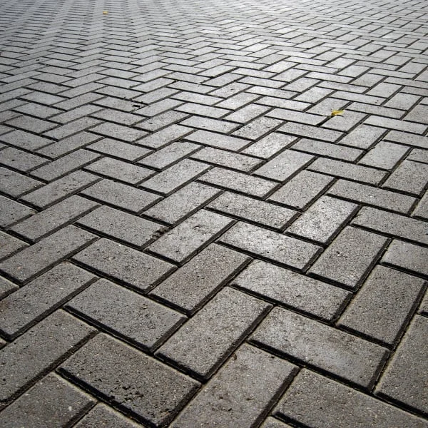 Šedá dlažba z klinkerových kostek v šachovnicovém vzoru.