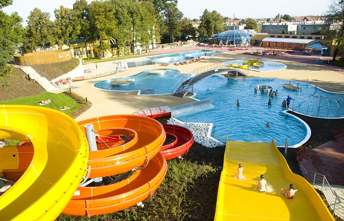 Venkovní akvapark s barevnými vodními skluzavkami a bazény.