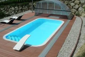 Zapuštěný bazén s dřevěnou terasou a krycí konstrukcí.