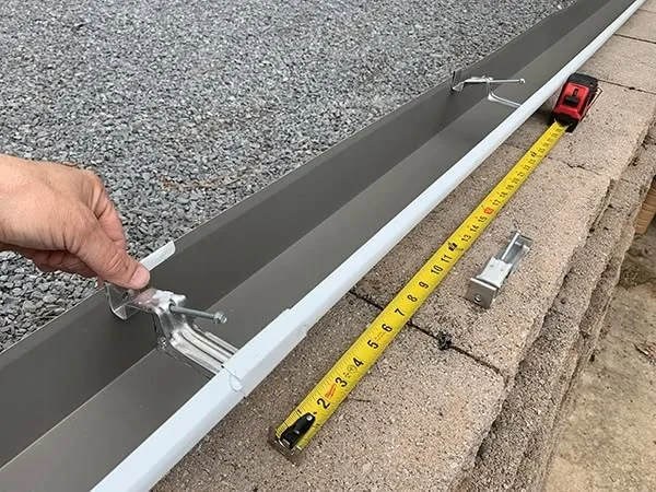 Montáž okapu svépomocí s držáky a měřicí páskou.