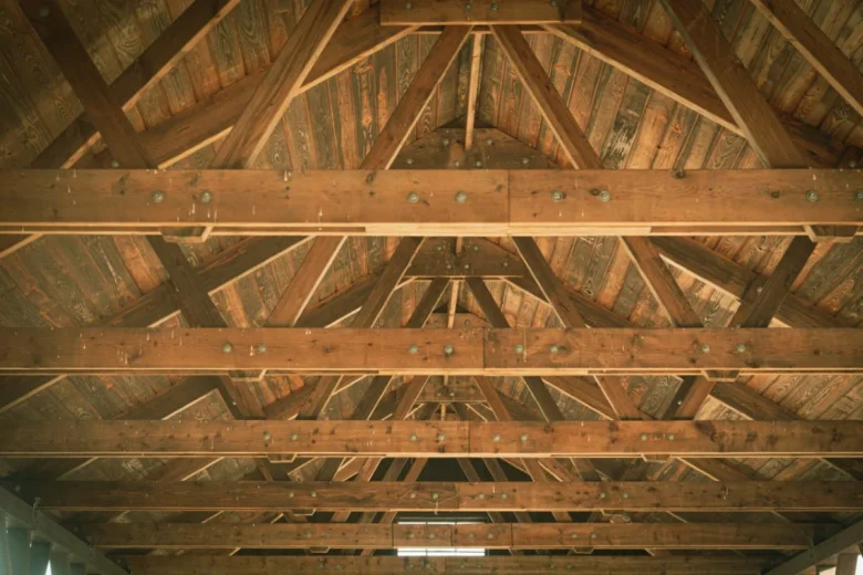 Detailní fotografie dřevěných trámů tvořících konstrukci střešní krovu.