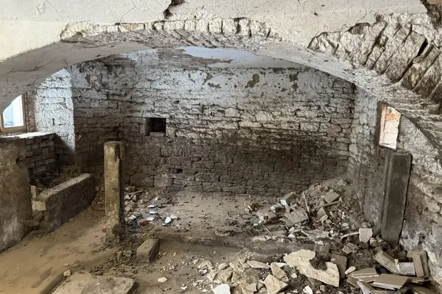 Poškozená kamenná zeď v interiéru potřebující sanaci a opravu.