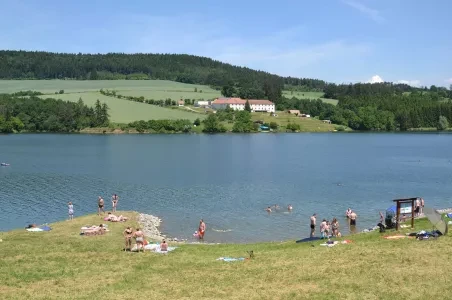 Přírodní koupaliště na jižní Moravě s lidmi v jezeře.