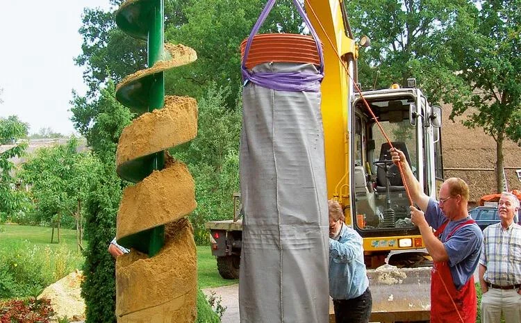 Bager zvedá pytel s pískem pro technické instalace.