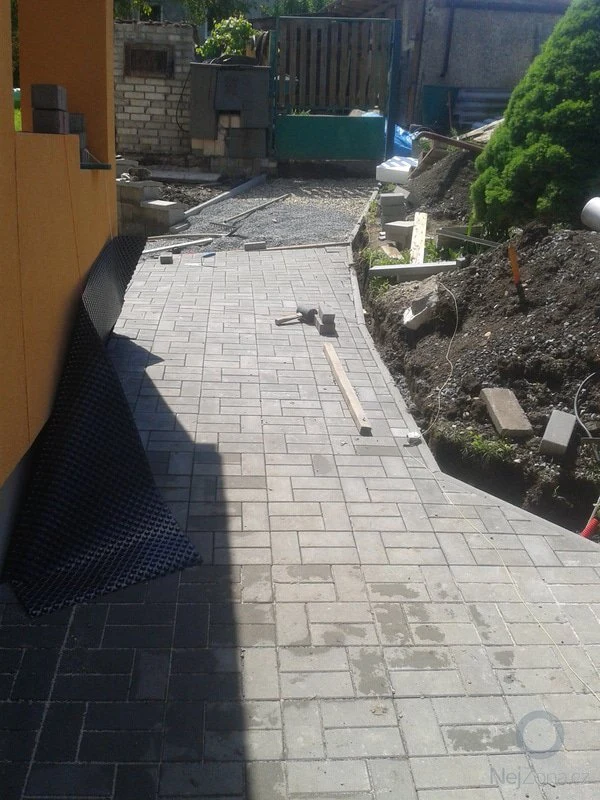 Pokládka zámkové dlažby s nástroji a materiály na místě.