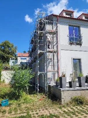 Dvoupatrový dům v rekonstrukci s opěrným schodištěm.