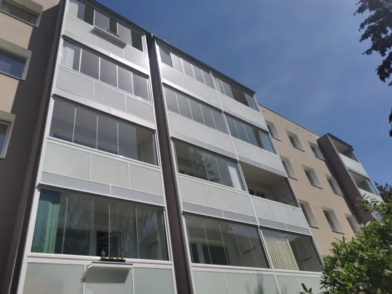 Moderní balkony s výplněmi z skla po rekonstrukci v bytovém domě.