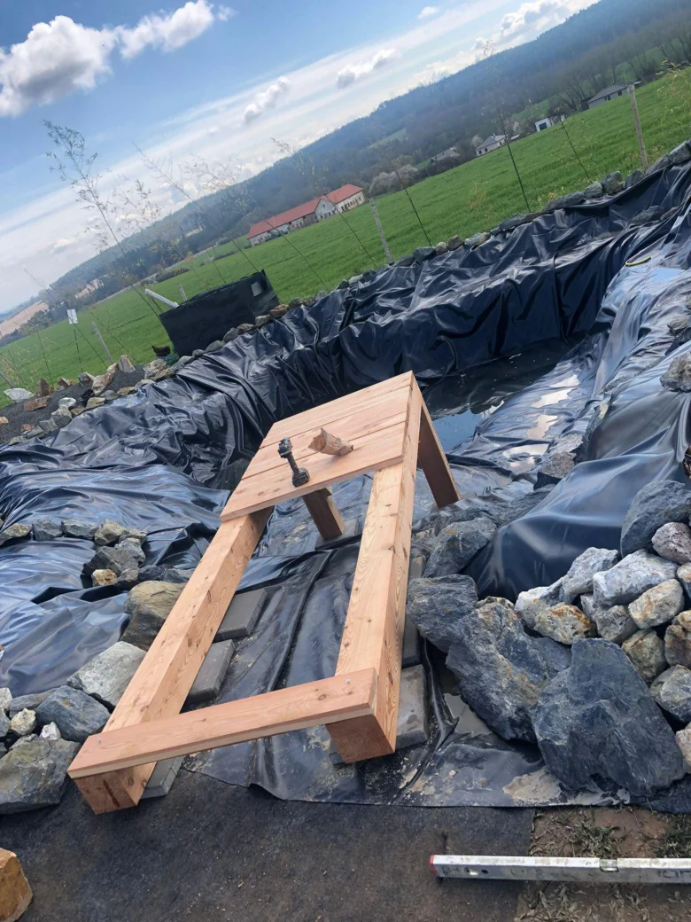 Dřevěný rám pro koupací sud postavený vlastními rukama na venkovním místě.