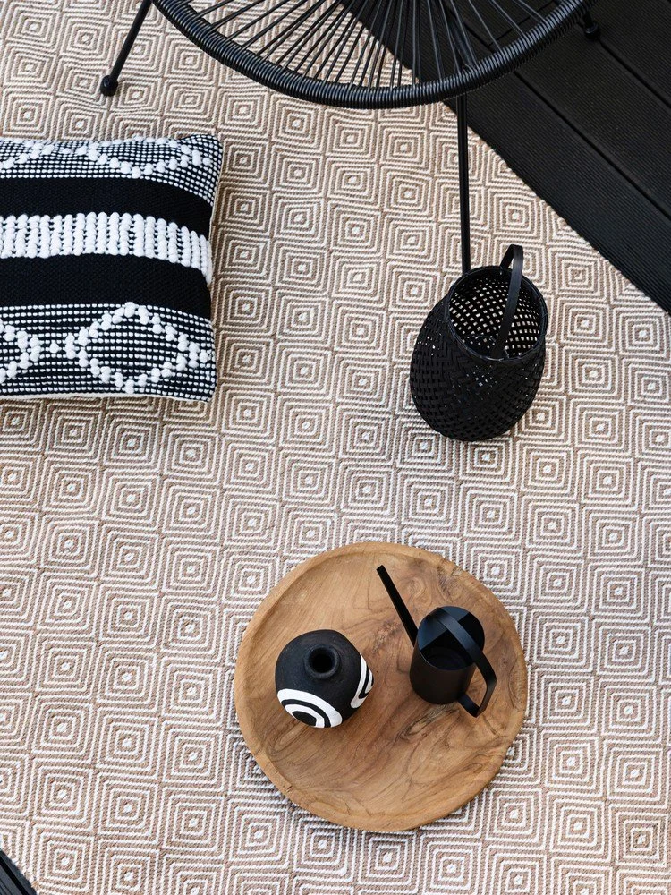 Balkon s geometrickým kobercem, dekorací a nábytkem.