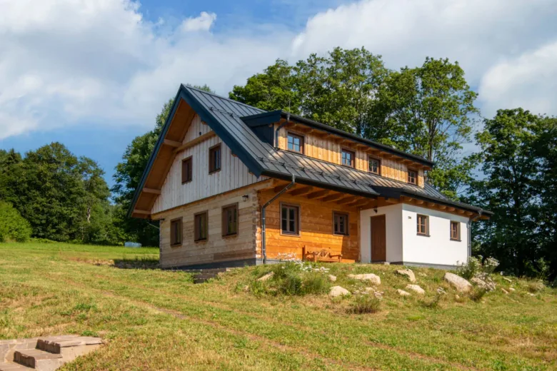 Moderní roubená stavba na svahu s dřevěnou fasádou.