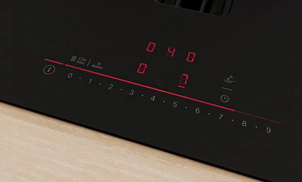 Detailní záběr na ovládací panel indukční varné desky s červenými číslicemi.