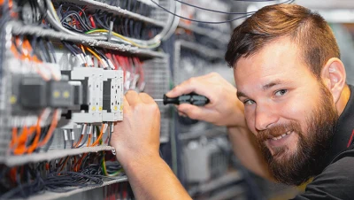 Elektrikář pracuje na elektrorozvaděči s kabely a komponentami.