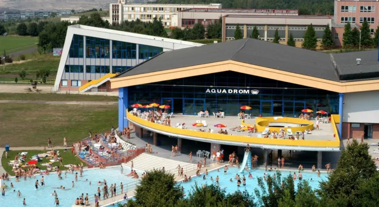 Vnější pohled na bazénový komplex Aquadrom v Mostě s lidmi.