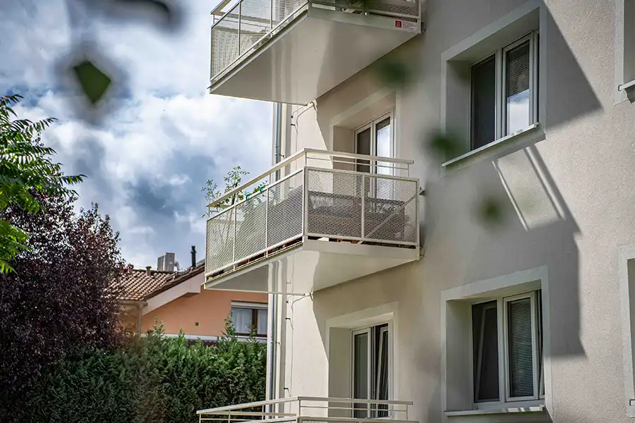 Moderní balkony s kovovými zábradlím a květinami po rekonstrukci.
