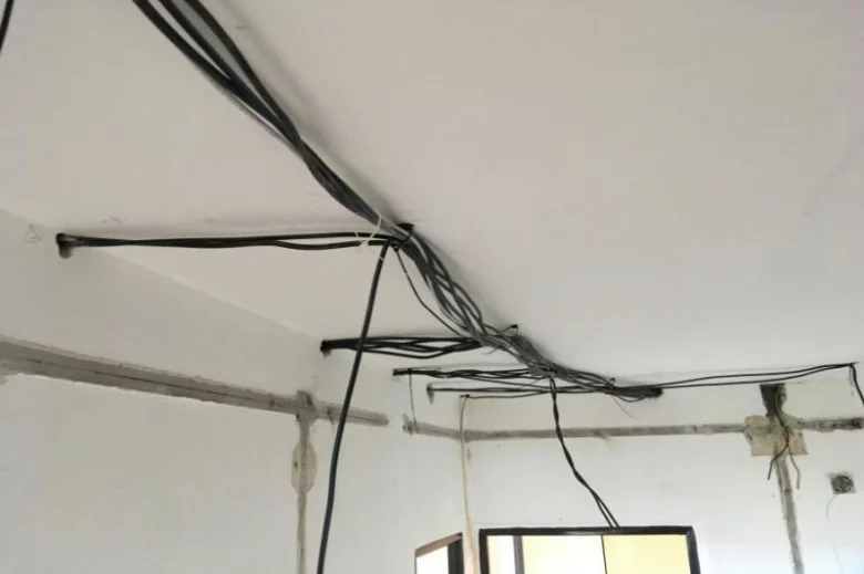 Přehnané elektrické kabely na stropě v bytě během rekonstrukce.