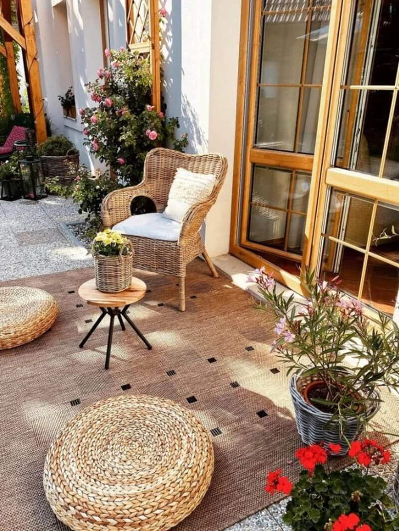 Balkon s kobercem, ratanovým nábytkem a květinami.