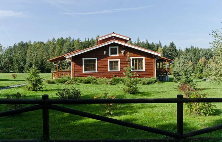 Tradiční červený finský dřevěný domek v zelené louce.