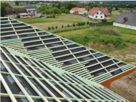 Montáž difuzní folie na střešní konstrukci v procesu izolace.