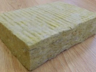 Žlutý blok čedičové vlny na dřevěné podlaze.