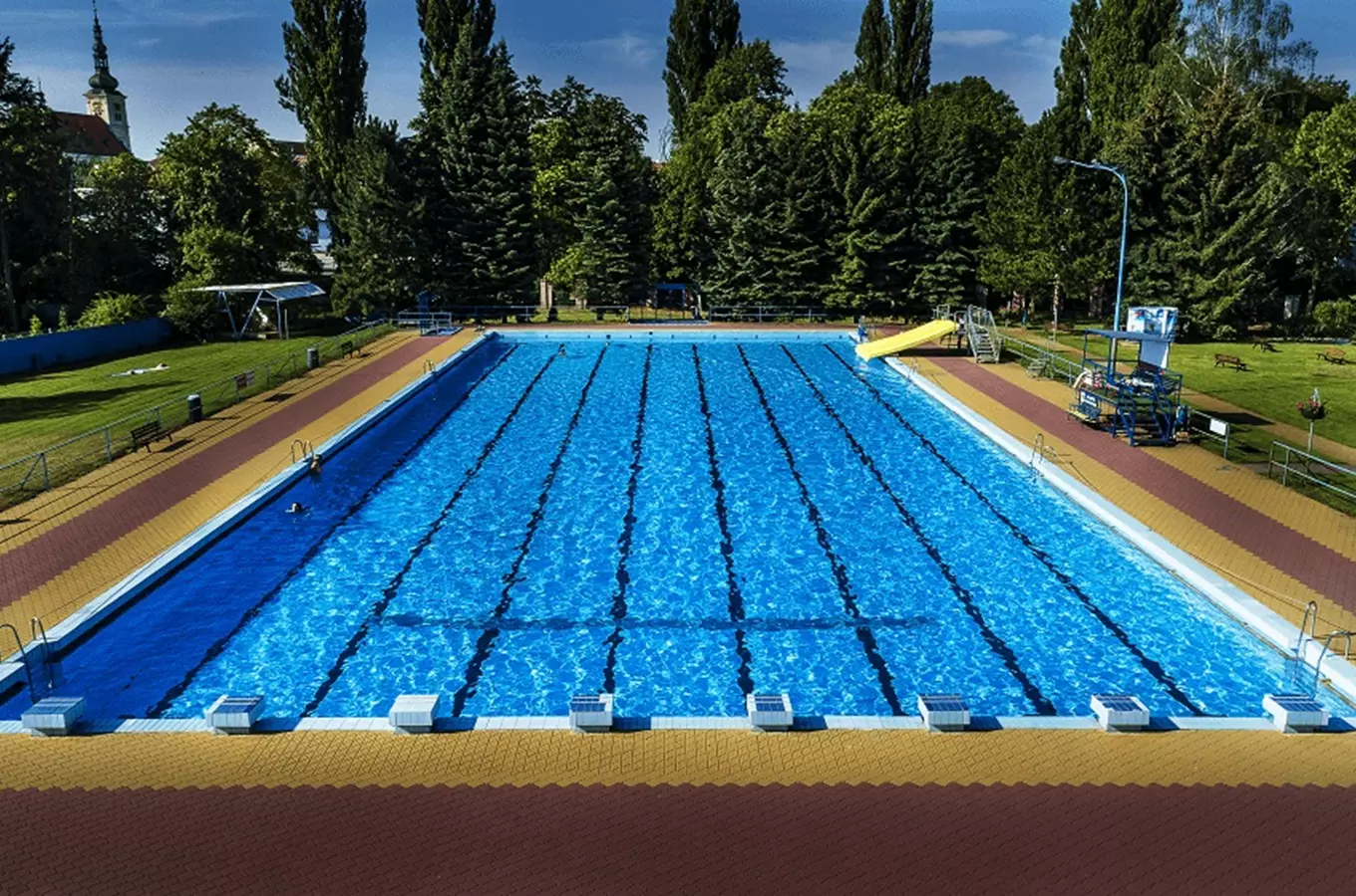 Venkovní plavecký bazén s dálnicemi a žlutým skluzavkou ve Vyškově.