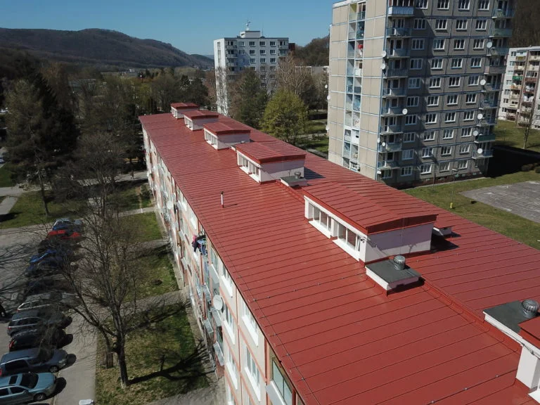 Červená pultová střecha bytovky ukazuje minimální sklon.