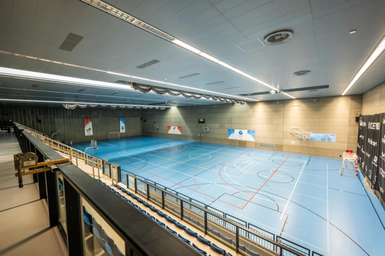 Vnitřní sportovní hala s modrým parketem pro basketbal.
