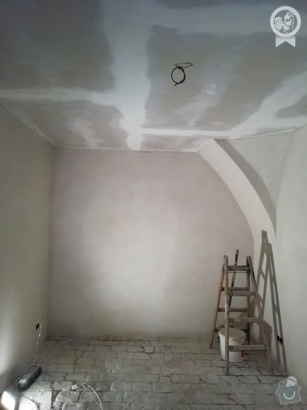 Průběh rekonstrukce místnosti s omítkou na stěnách a podlaze.