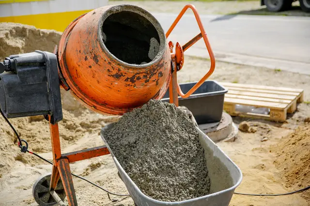 Směšovač betonu nalévá čerstvý beton do vozíku na staveništi.