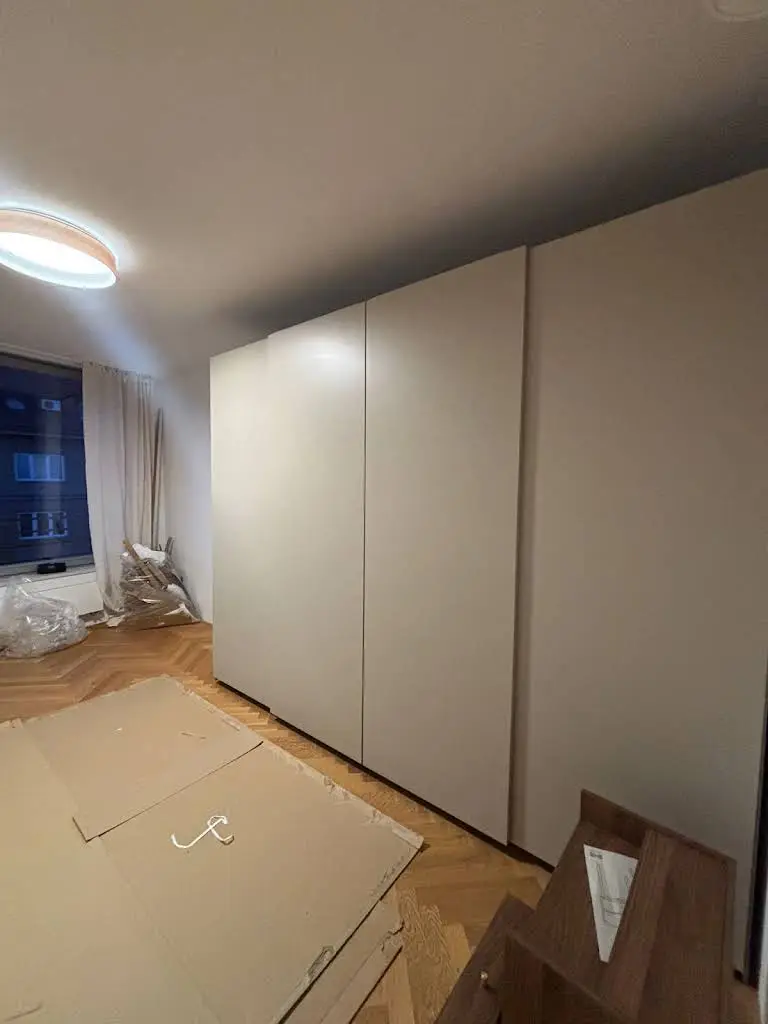 Montáž bílých skříní v interiéru s kartonovými obaly.