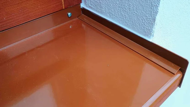 Hnědý vnitřní parapet připevněný ke zdi.