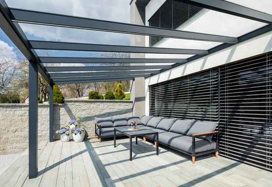 Moderní hliníková pergola s venkovním sedacím nábytkem na terase.