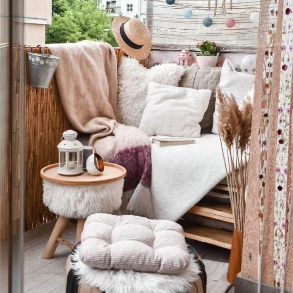 Uspořádaný balkon s dřevěnou podlahou a měkkým nábytkem.