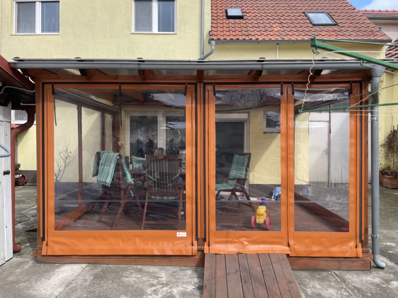 Oranžová plachta na dřevěné pergole v zahradním domku.