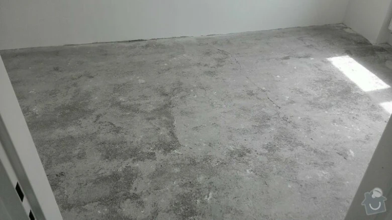 Prázdná místnost s betonovou podlahou připravenou na rekonstrukci.