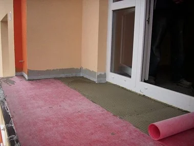 Balkon v rekonstrukci s rolovanou izolační vrstvou před lepením dlažby.