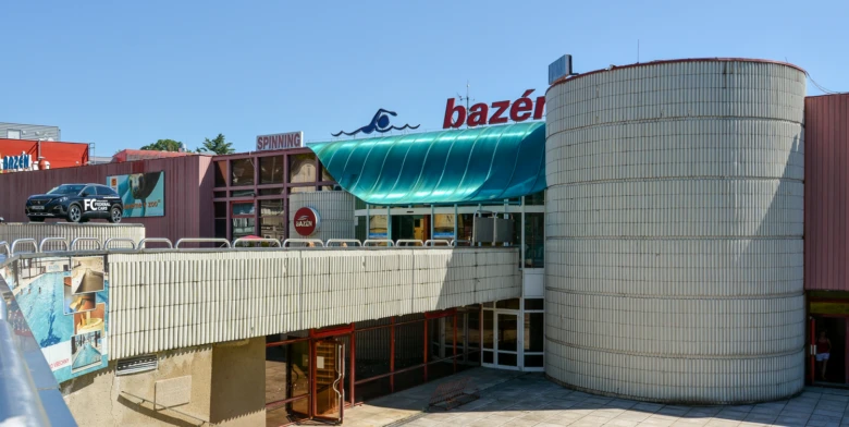 Exteriér plaveckého bazénu v Liberci s cylindrickou budovou.